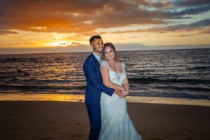 bride and groom on beach during sunset