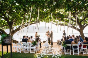 Couple getting married under trees by the ocean