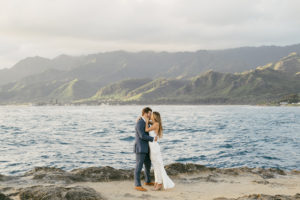 Bride and Groom Kissing by the Ocean and Hawaiian mountains by Rachel Kathyrn