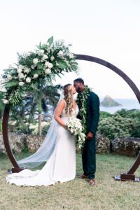 Bride and Groom Kissing Under Decorative Wedding Arch