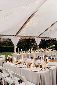 Wedding Tables Decorated with candles and flowers under a white tent set up by Tropical Moon Events
