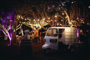 Aloha Taps Mobile bar placed at A night time wedding reception under the trees lit up with some hanging lights