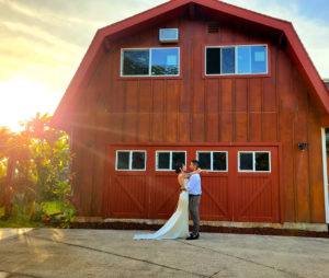 bride and groom standing by barn