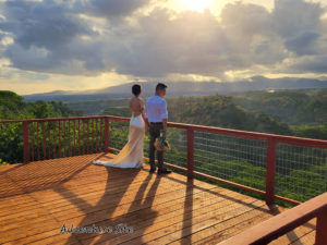 A couple standing on a deck, gazing out over lush, green nature at Hawaii Vista Weddings Venue