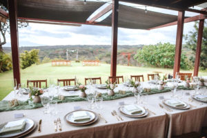 A table at a Hawaii Vista wedding reception, decorated with plates and delicate floral arrangements