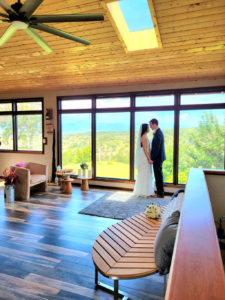 A couple sharing an intimate gaze at a room with floor to ceiling windows looking over the lush gardens of Hawaii Vista Wedding venue