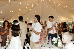 A Wedding celebration inside a white tent with hanging lights at Hawaii Polo Club