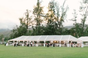 A wedding setting with a white tent on lawn surrounded with trees at hawaii polo club