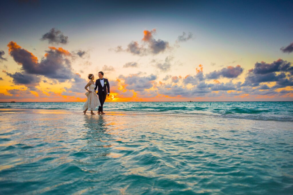 Bride and groom walking on a beach during sunset