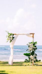 Wooden Arch decorated with white drapes and white flowers in an oceanfront setting