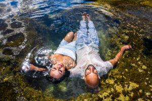 A couple laying in shallow water captured by Shannon Sasaki Photography