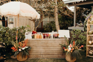 A chic wooden bar full of cocktail mixers surrounded by tropical plants at a wedding in Hawaii