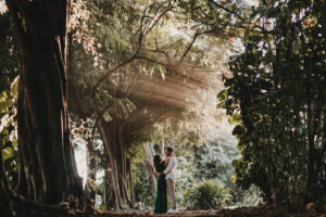 A couple hugging and looking into each others' eyes surrounded by tropical trees captured by Seeking Films