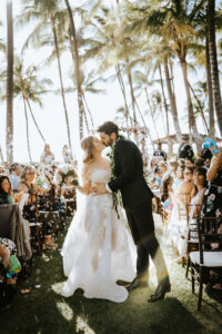 Wedding couple kissing in front of their wedding guests at an outdoor wedding in Hawaii captured by Seeking Films