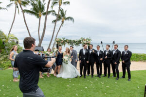 Bride and Groom with their Bridesmaids and Groomsmen being videographed by Aloha Films at a beach wedding in Hawaii